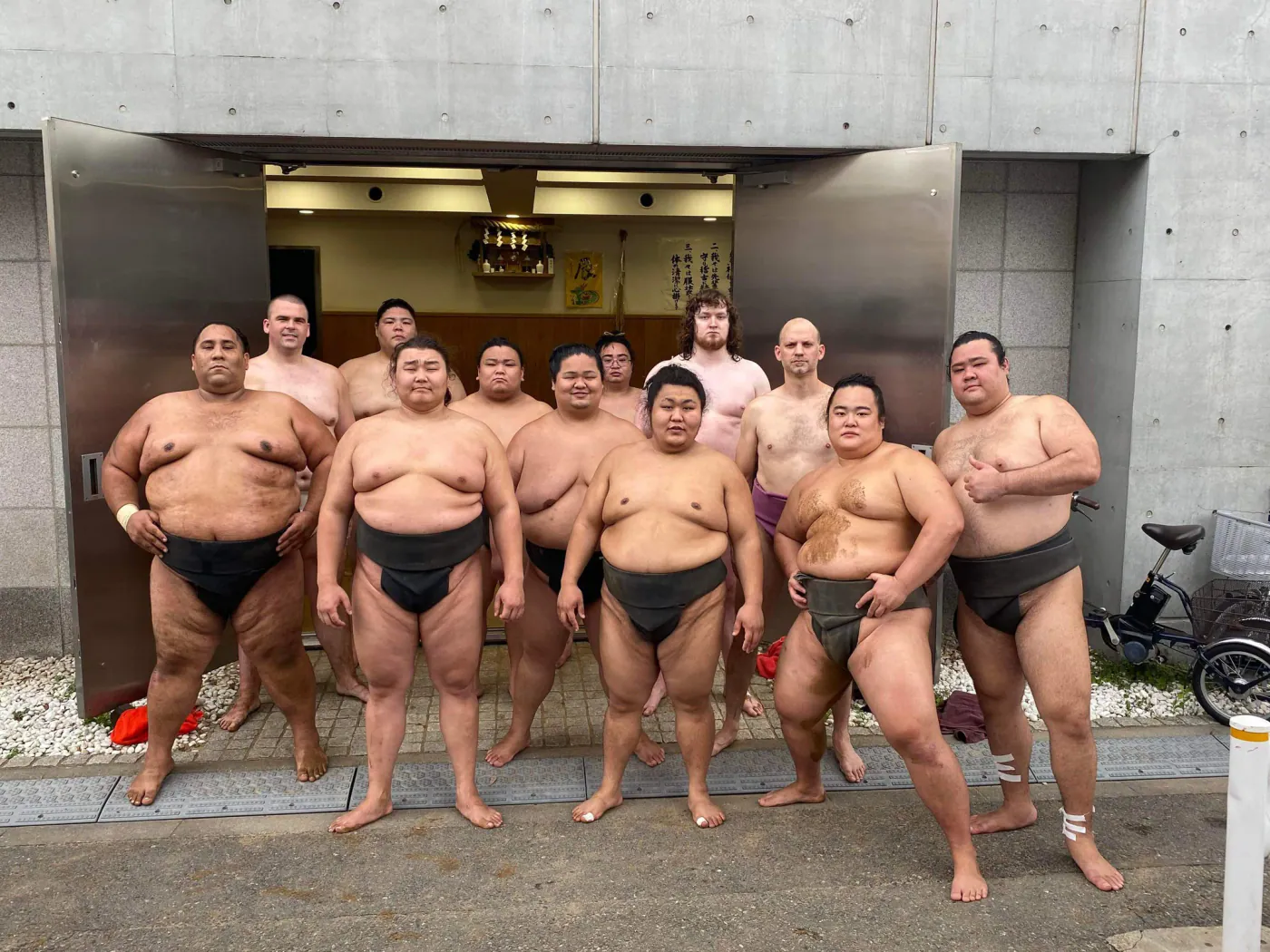 Wrestlers standing in the open doorway of a sumo stable